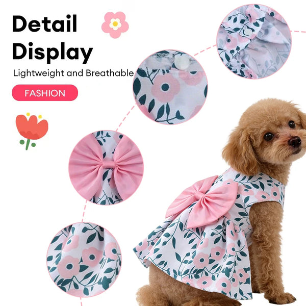 A small dog wearing a pink floral print dress with a large bow detail.