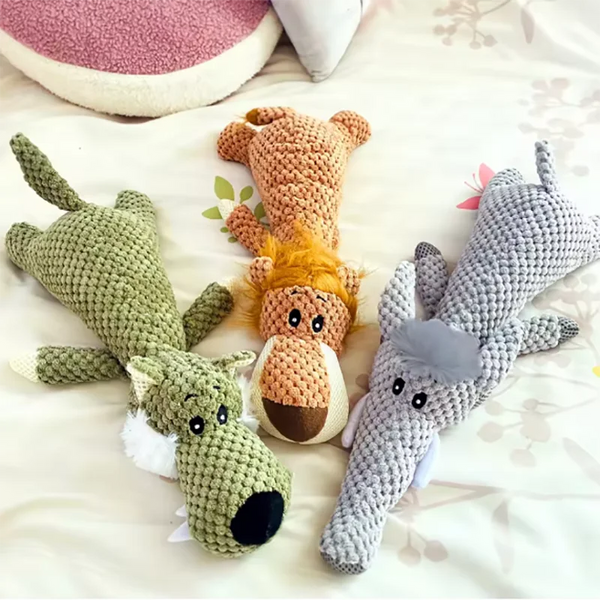 A set of bite-resistant plush dog toys including a green fox, a brown bear, and a gray wolf lying on a white surface.
