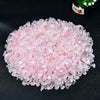 A pile of pink rose quartz crystal chips scattered on a dark surface.
