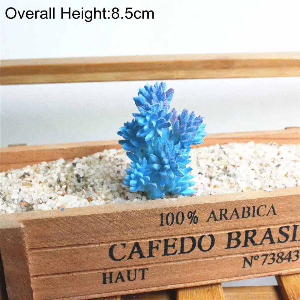 Blue artificial succulent plant in a wooden planter filled with light gravel.