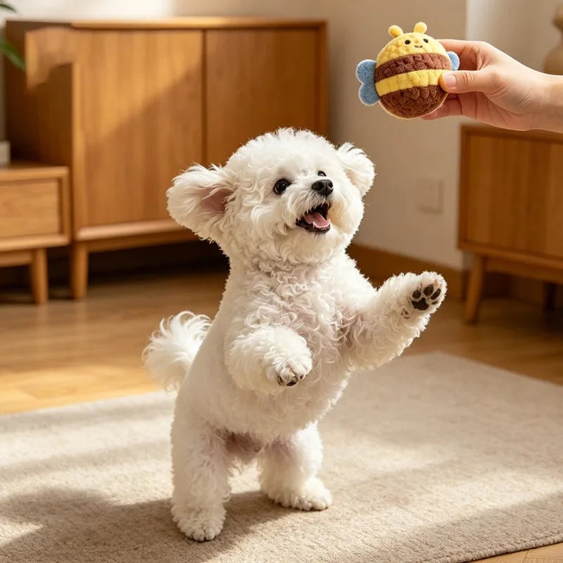 A fluffy white dog toy resembling a small bear is being held by a hand, with another similar toy visible in the background.
