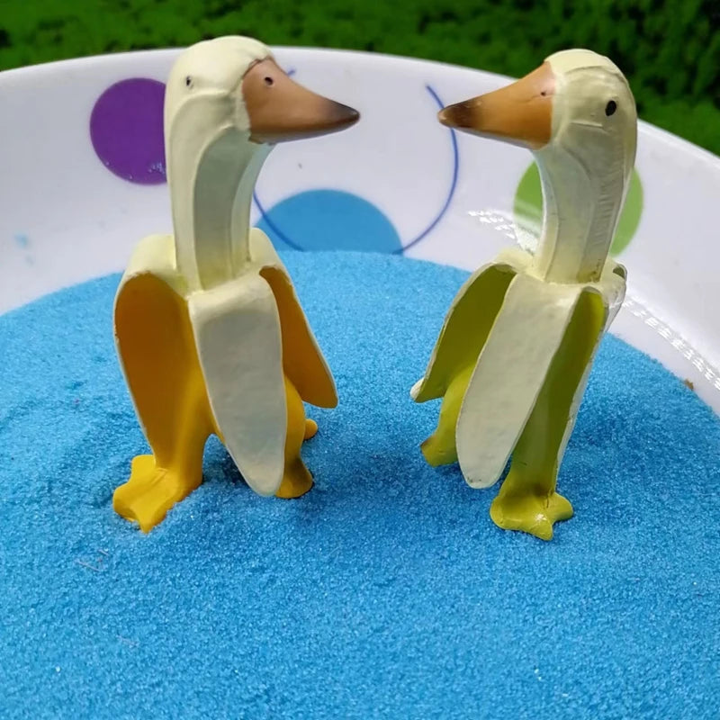 Zwei Keramik-Gartenskulpturen von Enten in Gelb und Weiß auf einer blauen Oberfläche.