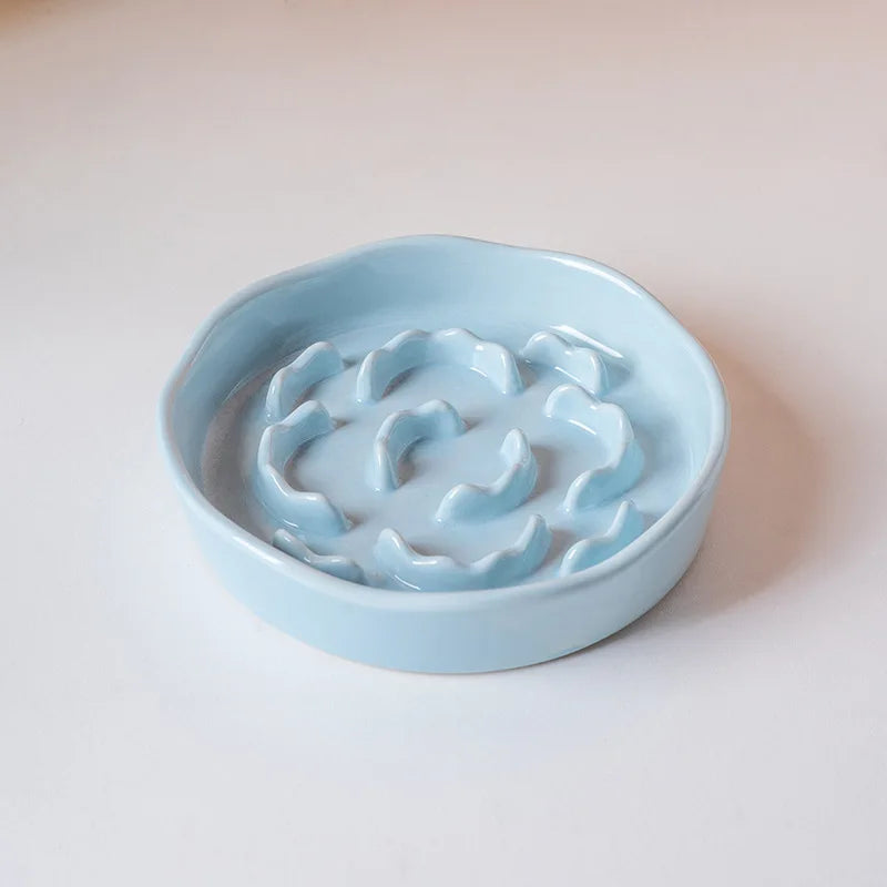 A light blue ceramic elevated bowl with a slow feeder design for cats or dogs.