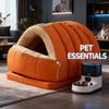 An orange pet bed is shown on a rug next to a modern electronic feeder for pets.