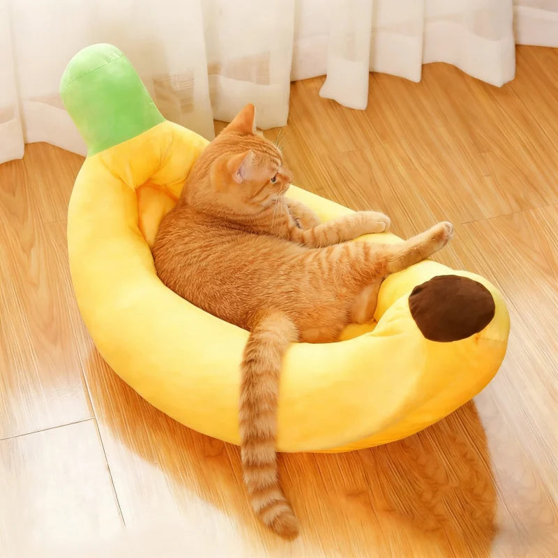 Un chat tigré orange se détend dans un lit en peluche de forme de banane jaune.