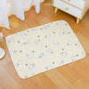A yellow pet cage mat with white rabbit designs is placed on a light wood floor.