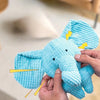 A hand is squeezing a light blue squeaky elephant plush toy for dogs.