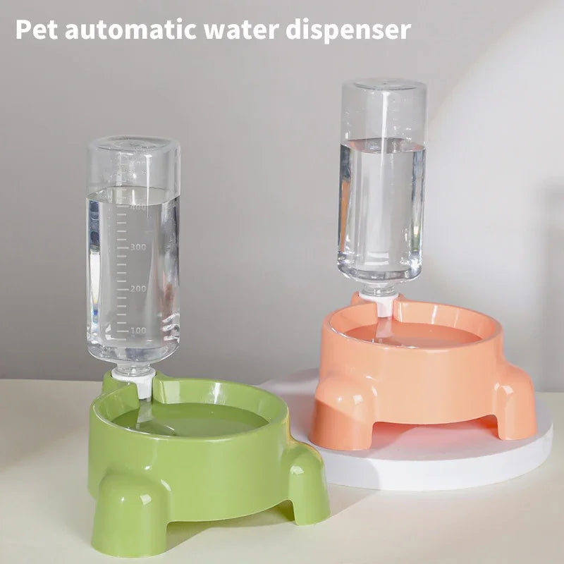 A clear glass automatic pet water dispenser with a measuring mark, sitting on an orange base and a green stand.