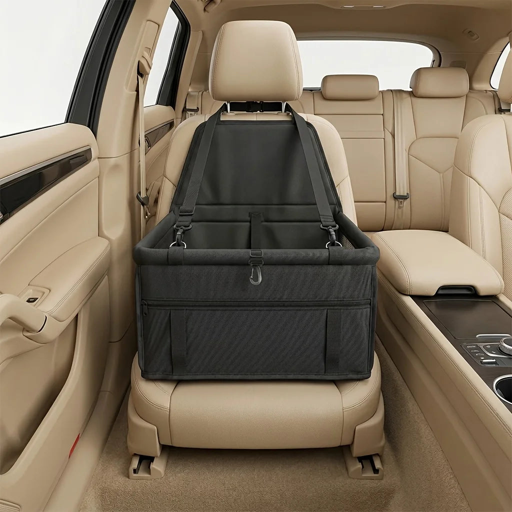 A portable dog car seat travel carrier in black fabric is shown in the rear seat of a light tan vehicle.