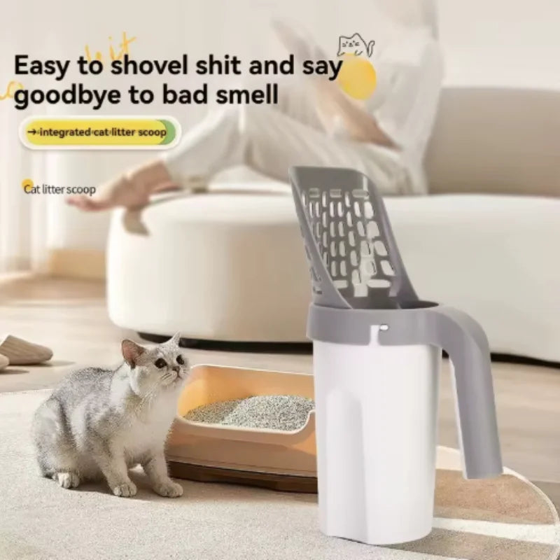 A gray cat is sitting next to a white plastic litter scoop with a filter, demonstrating its use for scooping cat litter.