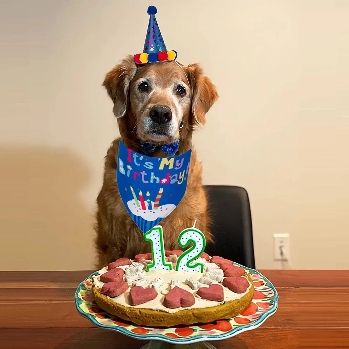 Ein goldener Retriever mit Partyhut schaut auf eine Geburtstagstorte mit Kerzen und rosa Zuckerguss.