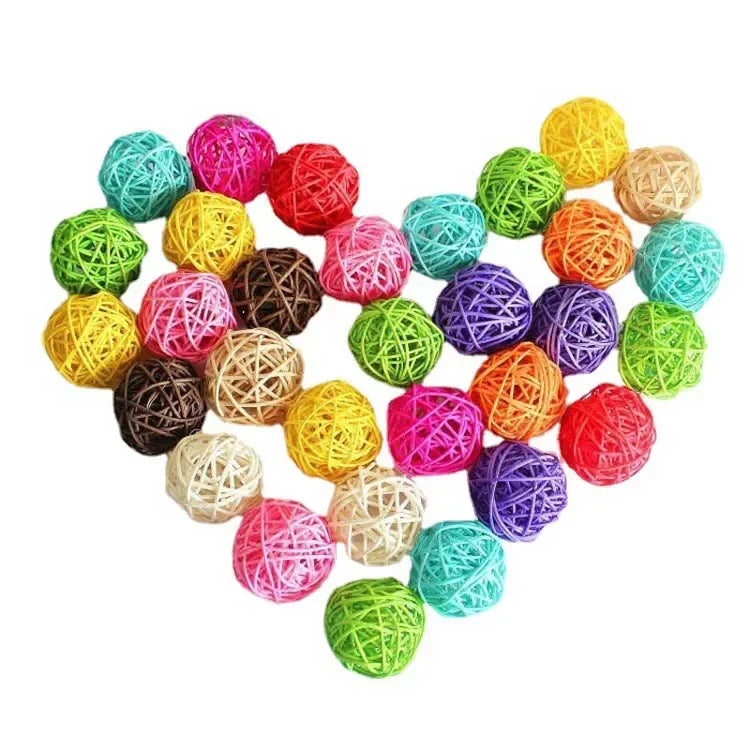 A collection of colorful natural rattan chewing balls for parrots arranged in a heart shape.