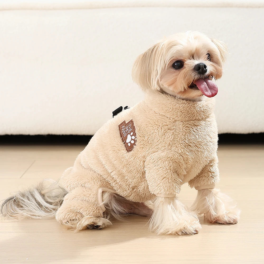 A light tan dog wearing a cozy fleece jumpsuit with a brown patch on its chest.