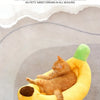Un chat orange et duvete relaxe dans un lit de peluche jaune en forme de banane.