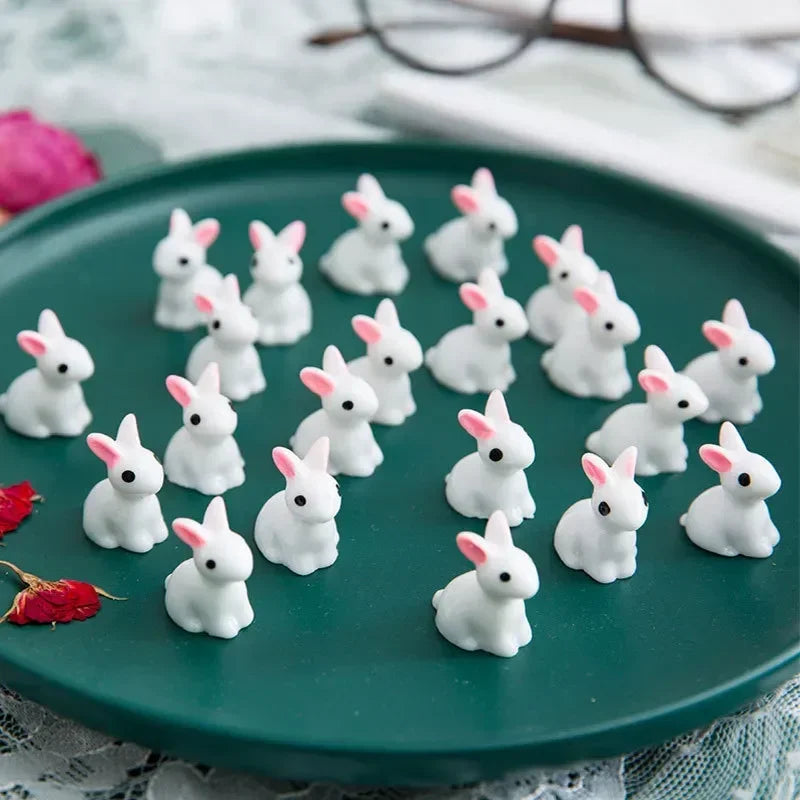 A plate of twenty white resin bunny figurines arranged on a green platter.