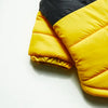 A yellow and black quilted winter coat for a dog, shown in a close-up view.