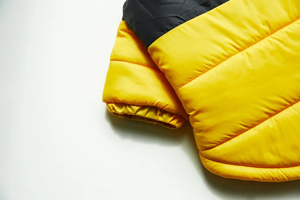 A yellow and black quilted winter coat for a dog, shown in a close-up view.