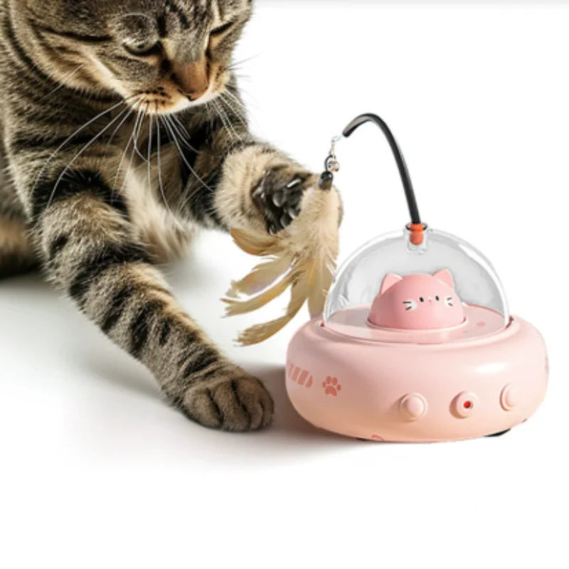 A tabby cat is interacting with a pink electronic toy designed to look like a cat head.