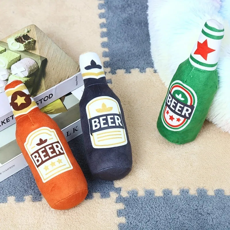 A funny beer bottle shaped squeaky dog toy in orange and dark blue colors resting on a fuzzy surface.