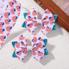 A pair of white and red patriotic star patterned ribbon hair bows with blue glitter accents displayed on a wooden surface.