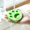 A hand holds a bright green reusable lint roller with holes, dripping water.