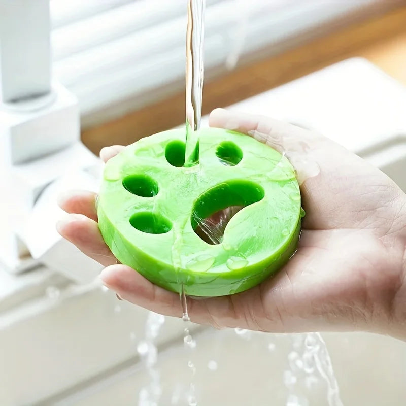 A hand holds a bright green reusable lint roller with holes, dripping water.