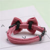 A pink plush velvet pet collar featuring a bow and bell, shown against a white background.