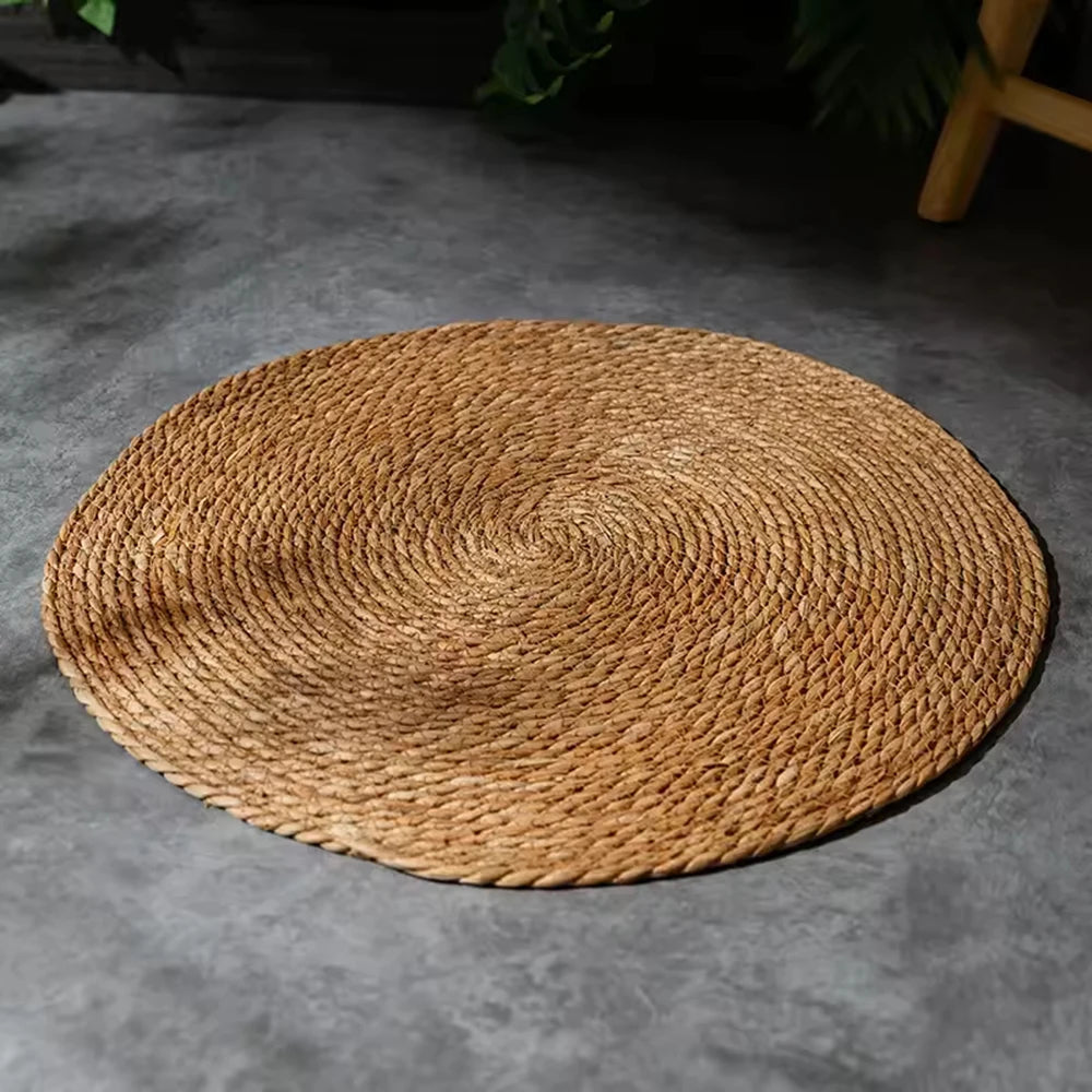 Round natural rattan cat scratcher mat lying on a gray surface.