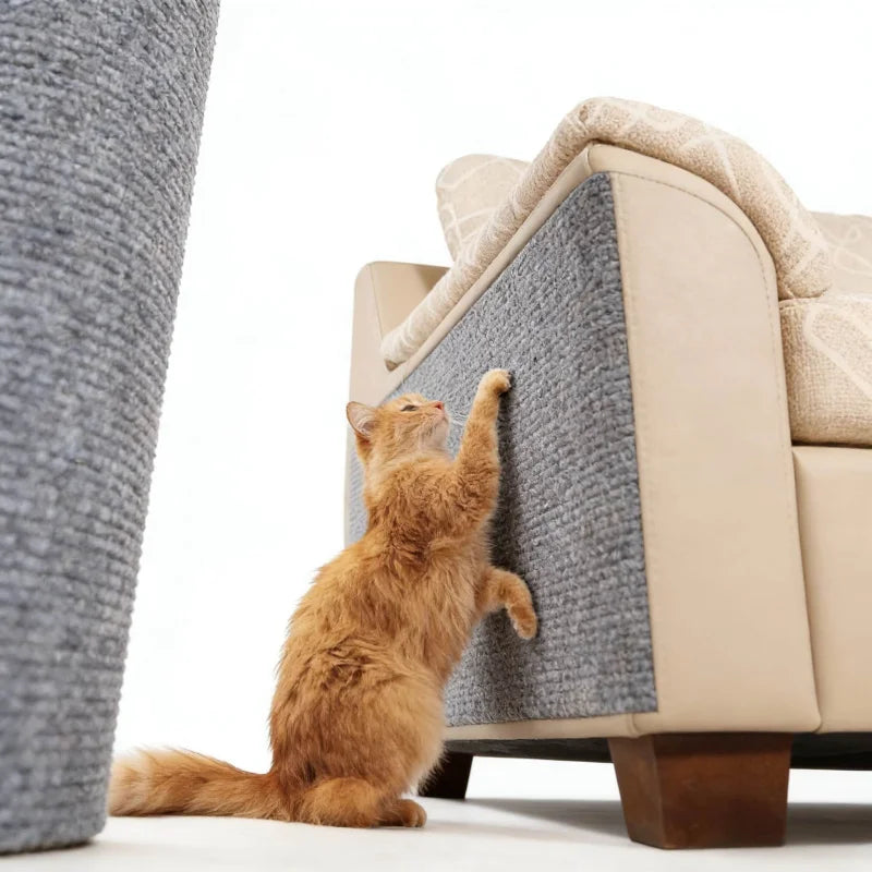 An orange tabby cat is climbing on a large gray self-adhesive sofa protector mat.