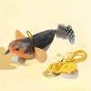 A small, dark and brown bird-like toy with a fluffy tail is shown against a light yellow background.