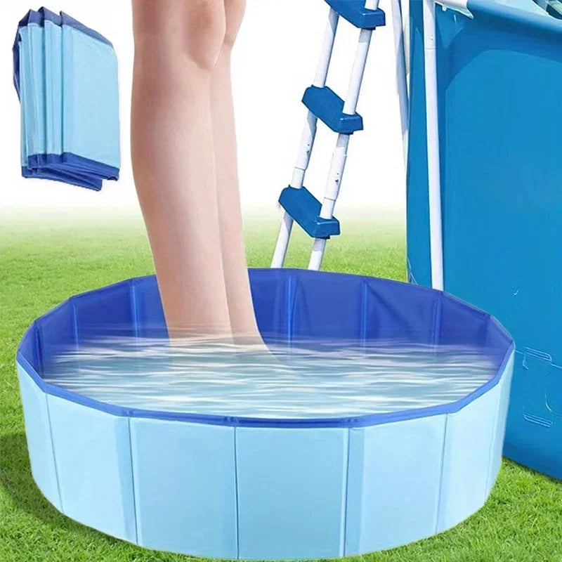 A blue foldable pet swimming pool filled with water, positioned on green grass.