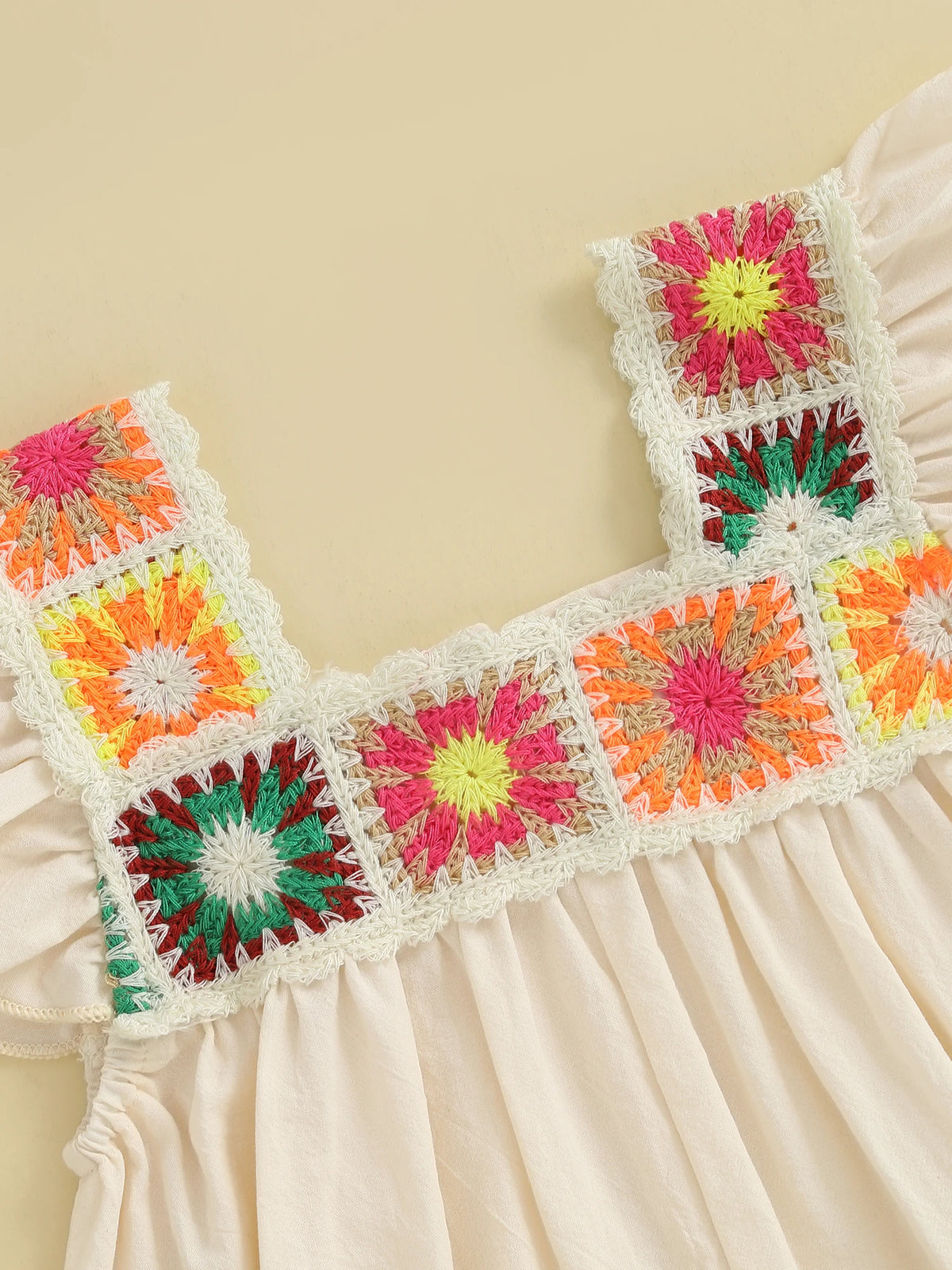 A light pink toddler romper featuring colorful floral embroidery with pink, yellow, and green accents.