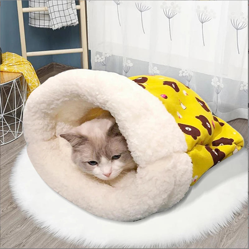 A fluffy white cat bed is shown nestled in a yellow patterned fabric, resting on a white rug.