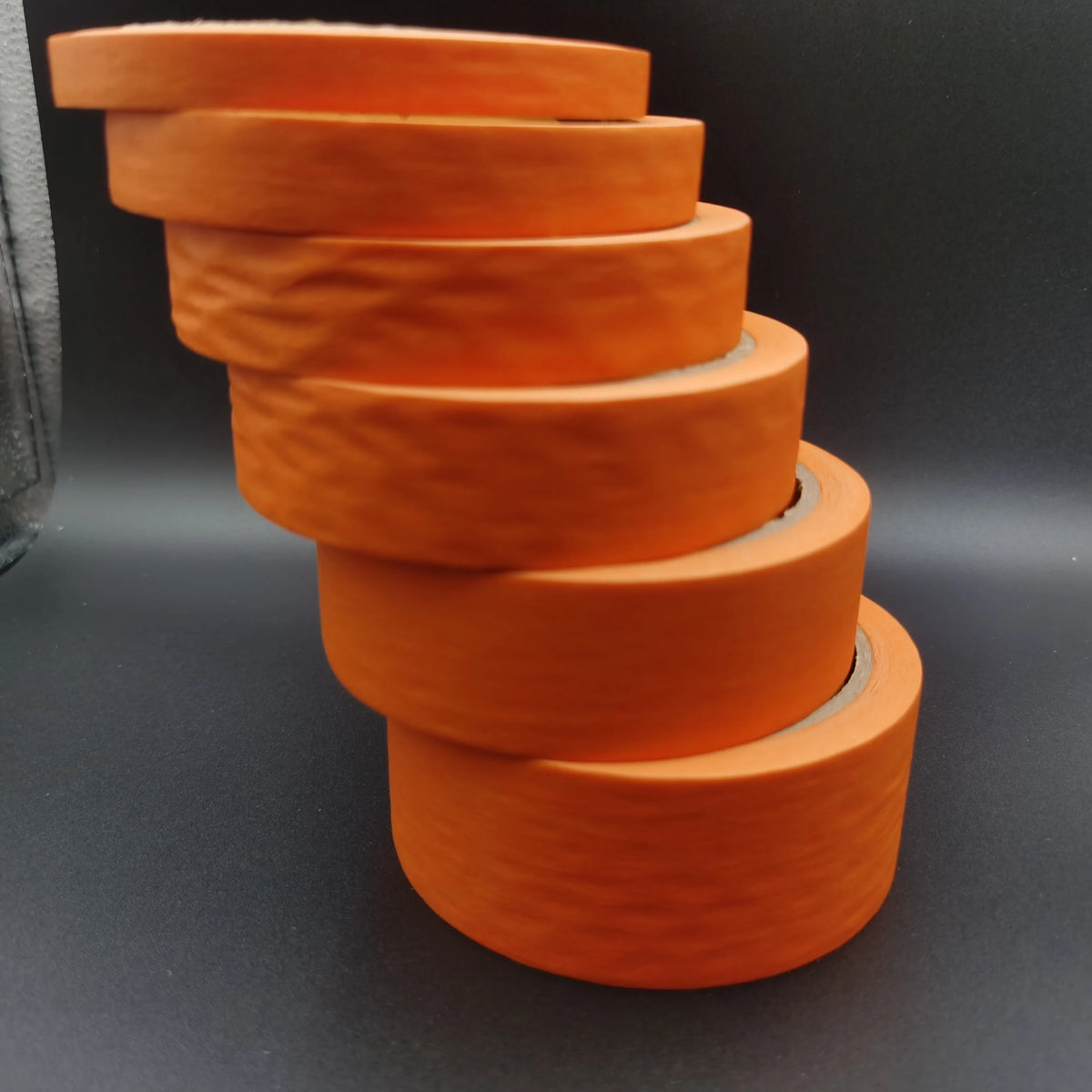 A stack of orange multi-surface masking tape rolls arranged in a pyramid shape.