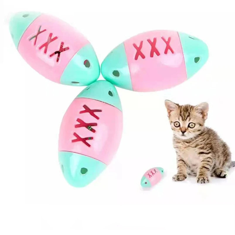 A set of ten pink and teal cat toy balls decorated with jingle bells, next to a small tabby kitten.