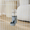 A clear automatic pet feeder waterer for dogs and cats is shown inside a wire mesh enclosure.