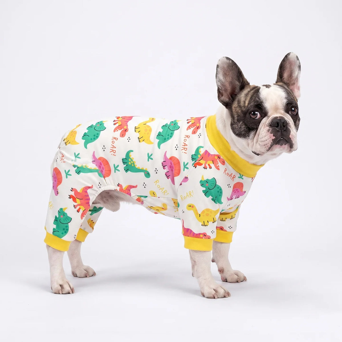 A British Bulldog wearing a yellow jumpsuit with an animal print featuring various colored animals.