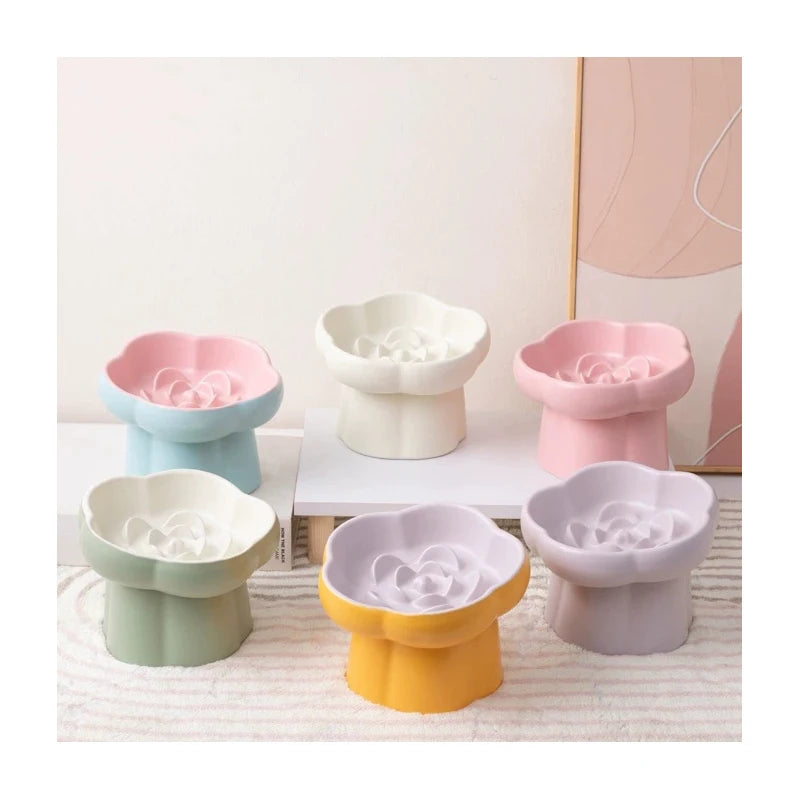 A collection of elevated ceramic slow feeder bowls for pets in various pastel colors including pink, mint green, and lavender