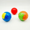 Three brightly colored squeaky rubber play balls for dogs: red, blue and orange-green.