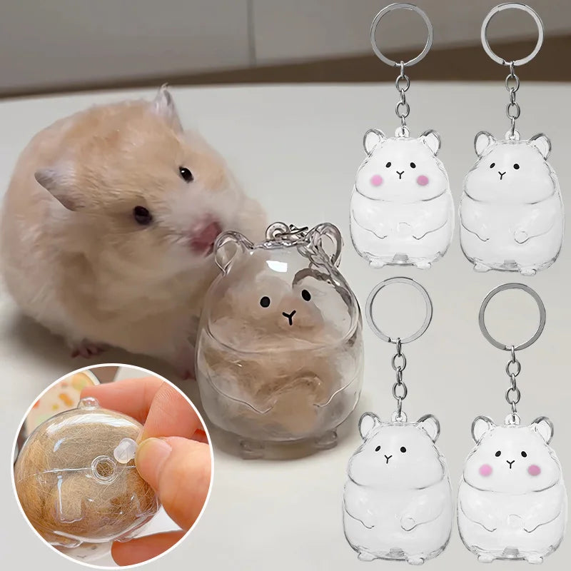 A fluffy pink hamster is shown next to clear glass figurines of hamsters, with a hand holding a small hamster keepsake keycha