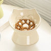 A white ceramic pet food bowl with a raised slanted design filled with dry kibble and white pieces.