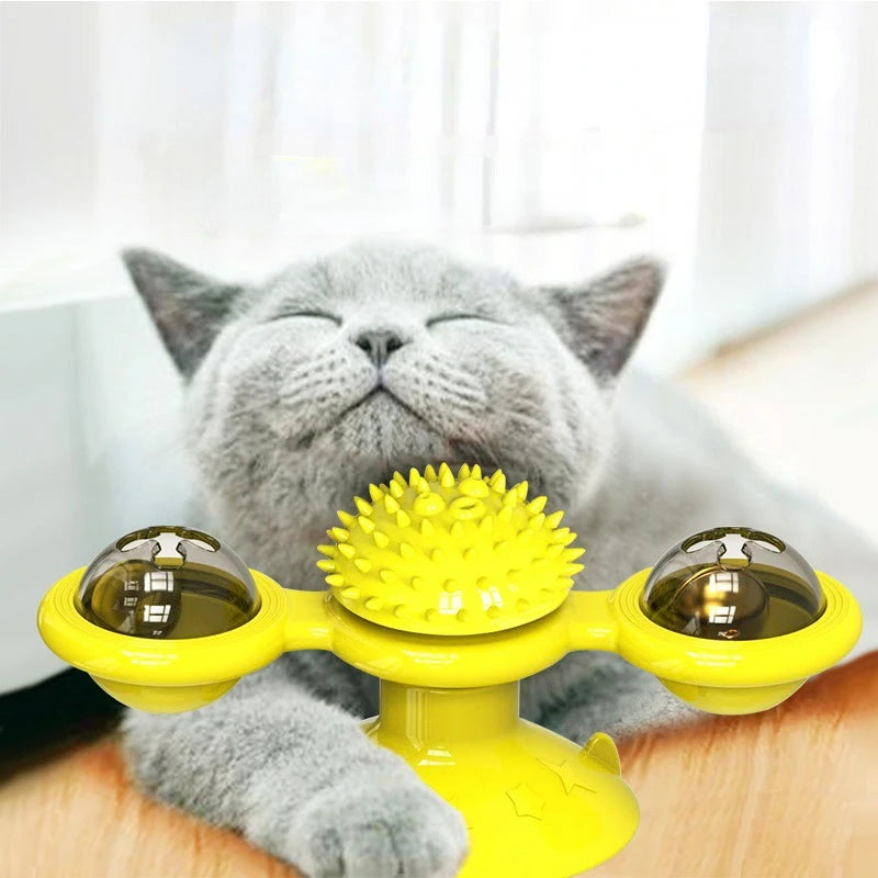 Un chat gris interagit avec un jouet sphérique en forme d'éolienne jaune pour jouer.
