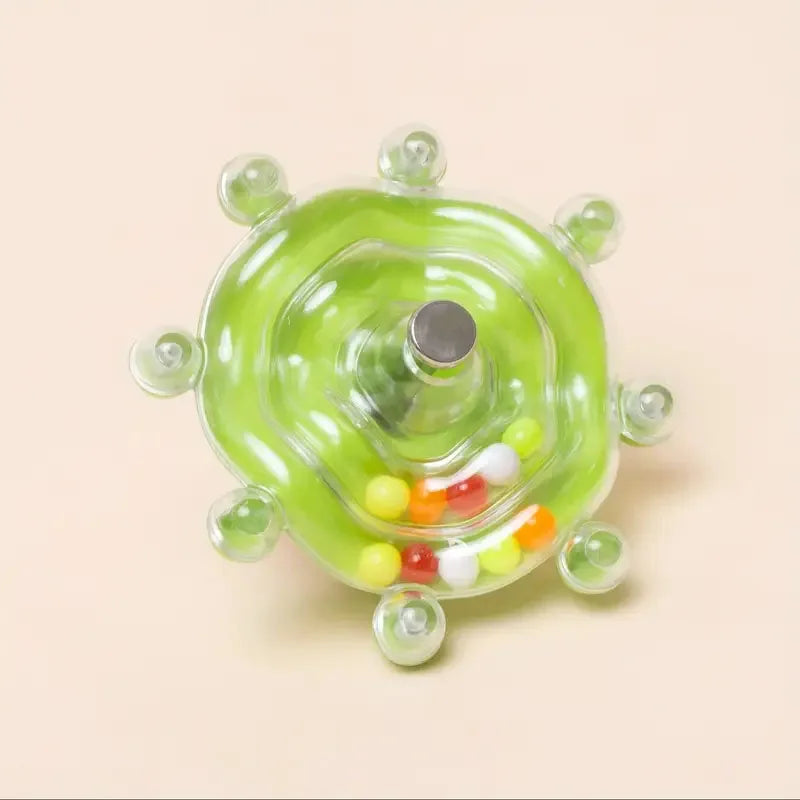 Klarer, runder, grüner Dispenser mit zentraler Öffnung und kleinen farbigen Kugeln unten.