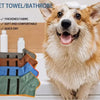 A happy dog looks at the camera next to a stack of pet towels and bathrobes.
