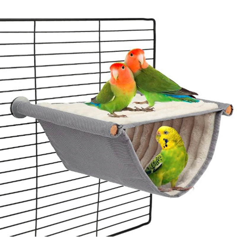 A cozy fleece bird hammock with two colorful parrots perched on it, hanging in a wire cage.