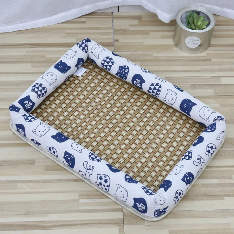 A rectangular pet bed with a white cotton mat and blue cat-themed fabric border, placed on a light wooden floor.