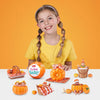 A smiling girl holds a pumpkin patch set featuring miniature baby dolls and pumpkins.