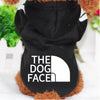 A black cozy fleece pet hoodie with the text THE DOG FACE printed on the back, worn by a brown dog.