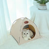 A beige foldable outdoor cat tent with an entrance for a small cat resting inside.