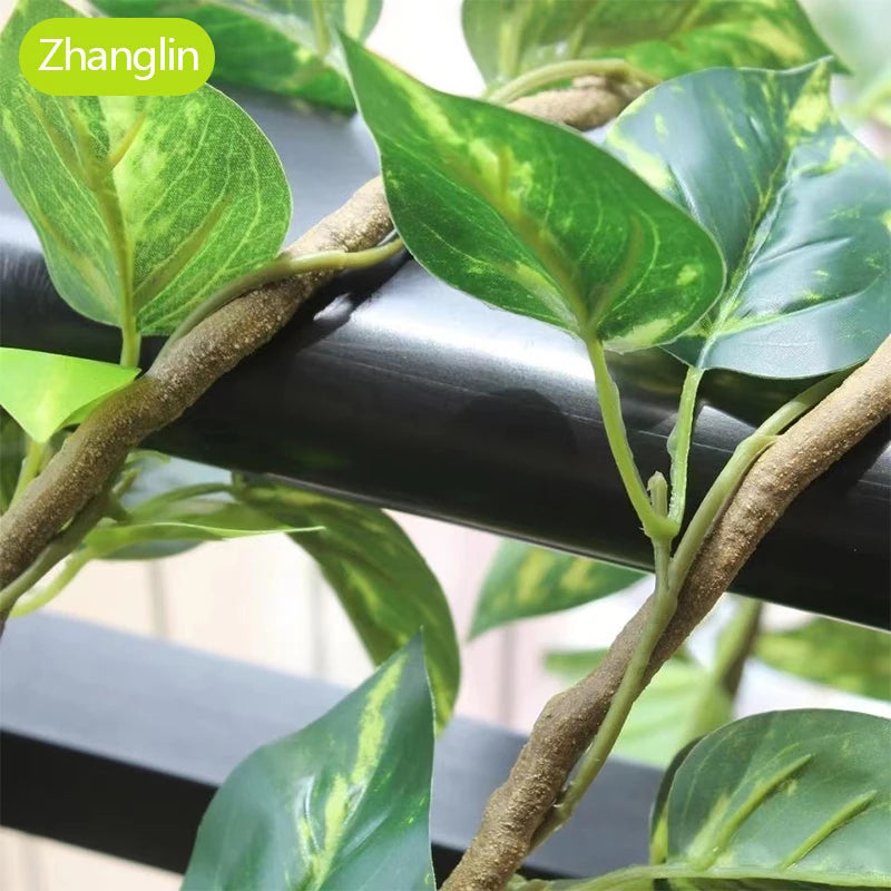Artificial green vine wall hanging decor featuring variegated green leaves growing on a woody stem.